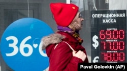 RUSSIA -- A woman walks past an exchange office screen showing the currency exchange rates of U.S. Dollar and Euro to Russian Rublel in Moscow, March 9, 2020