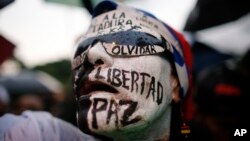 A woman with her face painted with Spanish words for; "Freedom, peace, don't forget," attends a vigil to honor the more than 90 people killed during three months of anti-government protests in Caracas, Venezuela, July 13, 2017.