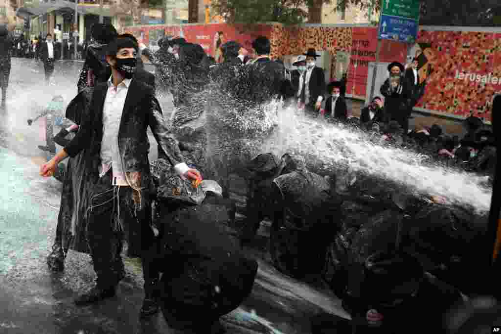 Israeli police shoot a water cannon toward ultra-Orthodox Jewish men blocking the road during a demonstration in Jerusalem.