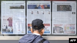 A man walks past a newspaper displayed on a street for the public in Seoul on October 21, 2024, with coverage on North Korea's decision to deploy thousands of soldiers to Ukraine. (Photo by Anthony WALLACE / AFP)