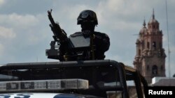 FILE - Federal police patrol mans a weapon atop a vehicle in Morelia, in the Mexican state of Michoacan Oct. 28, 2013.