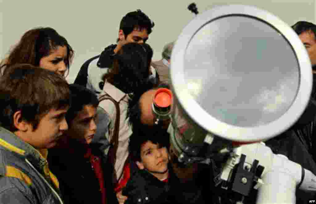 People uses a telescope, set by the Greek Astronomy Club to watch a partial solar eclipse outside outside the entrance of the Evgenidis Foundation's Digital Planetarium, in Athens, on Tuesday, Jan. 4, 2011. Greece experienced a partial solar eclipse star