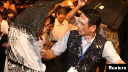 Security personnel protect Zhang Zhijun (C, in white shirt), director of China's Taiwan Affairs Office, with bullet-proof suitcases after anti-China protesters attempted to pour white paint on him in Kaohsiung, southern Taiwan, June 27, 2014. 