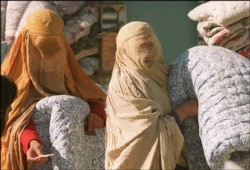 FILE - Afghan women, shown Nov. 19, 1996, in Kabul, wear Taliban-imposed burqas as they wait during a winter relief distribution. Scores of poor Kabul residents, notably women, were regularly seen huddled in front of aid agencies every day.