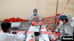 FILE - Men wear protective face mask as they work at a mask factory, during the coronavirus disease (COVID-19) outbreak in Kabul, Afghanistan, July 2, 2020. 