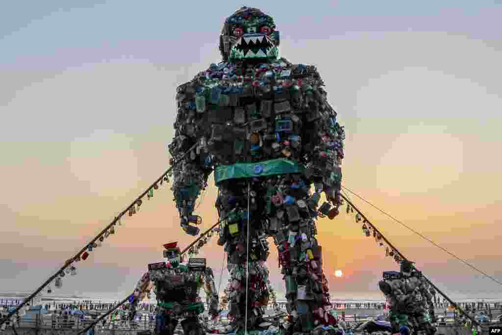 Orang-orang berjalan melewati patung raksasa &#39;Robot Monster&#39; yang terbuat dari sampah-sanpah plastik untuk meningkatkan kesadaran tentang bahaya pencemaran plastik di laut, di pantai Cox&#39;s Bazar, Bangladesh.(AFP)&nbsp;