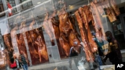 Pedestrians are reflected in the storefront window of a Chinese restaurant displaying roasted duck in downtown Lima, Peru, July 11, 2020, amid the new coronavirus pandemic.