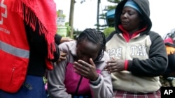 Kenya Red Cross personnel and relatives try to comfort a woman reacting near a burned-out dormitory, following a fire at the Hillside Endarasha Primary in Nyeri, Kenya, Sep. 6, 2024. 