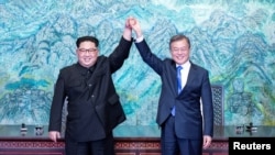 Tổng thống Hàn Quốc Moon Jae-in và lãnh tụ Triều Tiên Kim Jong Un nắm tay nhau đưa lên cao sau khi ký Tuyên bố chung Thượng đỉnh liên Triều ngày 27/4/2018 tại Bản Môn Ðiếm ở khu phi quân sự chia cắt hai miền Nam-Bắc Triều Tiên.