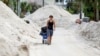 FILE - David DeMeza pulls his belongings through sand-lined streets after Hurricane Helene in Treasure Island, Florida, Oct. 2, 2024. 