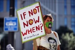 An Extinction Rebellion climate activist holds a placard during a "peaceful disruption" of British Parliament, in Manchester, England, Sept. 1, 2020.