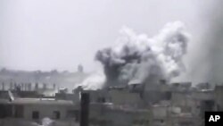 This image made from amateur video released by Ugarit News and accessed June 17, 2012, purports to show smoke rising from buildings in Rastan town, in Homs province, Syria. 