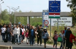 FILE - Migrants and refugees cross the border between Hungary and Austria, near Nickelsdorf, Austria, Sept. 10, 2015.