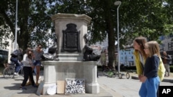 People look at the pedestal of the toppled statue of Edward Colston in Bristol, England, June 8, 2020, with joyous scenes, recognition of the fact that he was a notorious slave trader, a badge of shame in what is one of Britain’s most liberal cities.