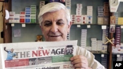 A fish-and-chips shop owner holds a copy of the New Age Newspaper which debuted Monday 06 Dec 2010 in Johannesburg with denials it is an agent of the governing African National Congress, (ANC)