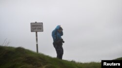 A man stands on a coastal cliff edge in the County Clare town of Lahinch, Ireland, Oct. 16, 2017.
