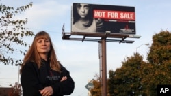 FILE - Dawn Stenberg, from the Junior League of Sioux Falls, stands near the group's anti-trafficking billboard in Sioux Falls, South Dakota, Oct. 27, 2015. About 50% of the women and girls falling prey to trafficking in the state are Native American.