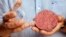FILE - Professor Mark Post holds the world's first lab-grown beef burger during a launch event in west London, Aug. 5, 2013. Mosa Meat, a Dutch company that presented the world's first lab-grown beef burger five years ago, said July 17, 2018, it has received funding to pursue its plans to make and sell artificially grown meat to restaurants from 2021.