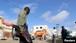 Un soldat somalien gardent les corps des victimes de l'attaque à la voiture piégée revendiquée par les shebab près de l'hôtel Nasahablood à Mogadiscio en Somalie, le 26 juin 2016.