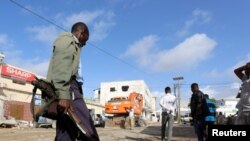 Un soldat somalien gardent les corps des victimes de l'attaque à la voiture piégée revendiquée par les shebab près de l'hôtel Nasahablood à Mogadiscio en Somalie, le 26 juin 2016.