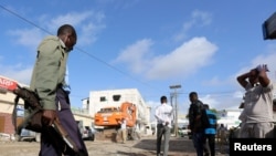 Un soldat somalien gardent les corps des victimes de l'attaque à la voiture piégée revendiquée par les shebab près de l'hôtel Nasahablood à Mogadiscio en Somalie, le 26 juin 2016.