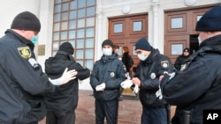 Policiers ukrainiens avant une opération de sécurisation près de l'aéroport de Kharkiv après l'évacuation de plus de 70 personnes de Chine en raison de l'épidémie de COVID-19, le 20 février 2020, (Photo AP/Igor Chekachkov)