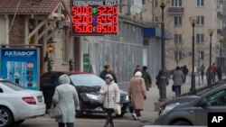 FILE - People walk past a currency exchange rate display in central Moscow, Dec. 1, 2014.