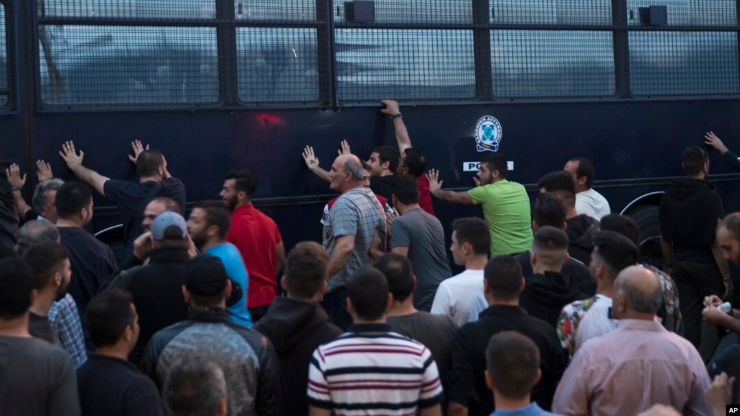Para pengunjuk rasa menggoyang-goyangkan bus polisi di kota Mytilene di bagian timur pulau yang terletak di Laut Aegea, yaitu pulau Lesbos, 3 Mei 2018 (foto: AP Photo/Petros Giannakouris)
