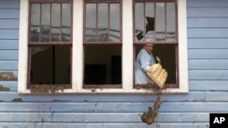 Ben Phillips scoops mud out a window of his house left in the wake of Hurricane Helene, in Marshall, North Carolina, Oct. 1, 2024.