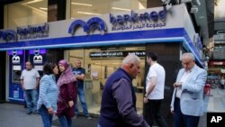 FILE - Clients wait outside a bank for its re-opening after a two-week closure, in Beirut, Lebanon, Nov. 1, 2019.