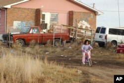 In this file photo, a young girl rides her bike on Pine Ridge Indian Reservation in southwestern S.D. on Tuesday , Jan. 10, 2006. At least 60% of Pine Ridge homes are substandard, lacking electricity, running water or sewage systems. (AP Photo...