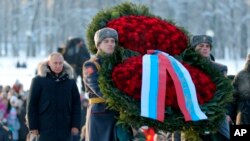 Russian President Vladimir Putin, left, takes part at a wreath laying ceremony at the Piskaryovskoye Cemetery, in St. Petersburg, Jan. 27, 2019, where most of the Leningrad Siege victims were buried during World War II. 