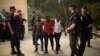 Police stand around a group of African migrants after they crossed the border fence from Morocco to Spain's North African enclave of Ceuta, Spain, Aug. 7, 2017.