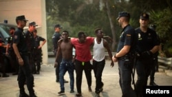 La police entoure un groupe de migrants africains à la frontalière entre le Maroc et l'enclave nord-africaine d'Espagne, Ceuta, en Espagne, le 7 août 2017