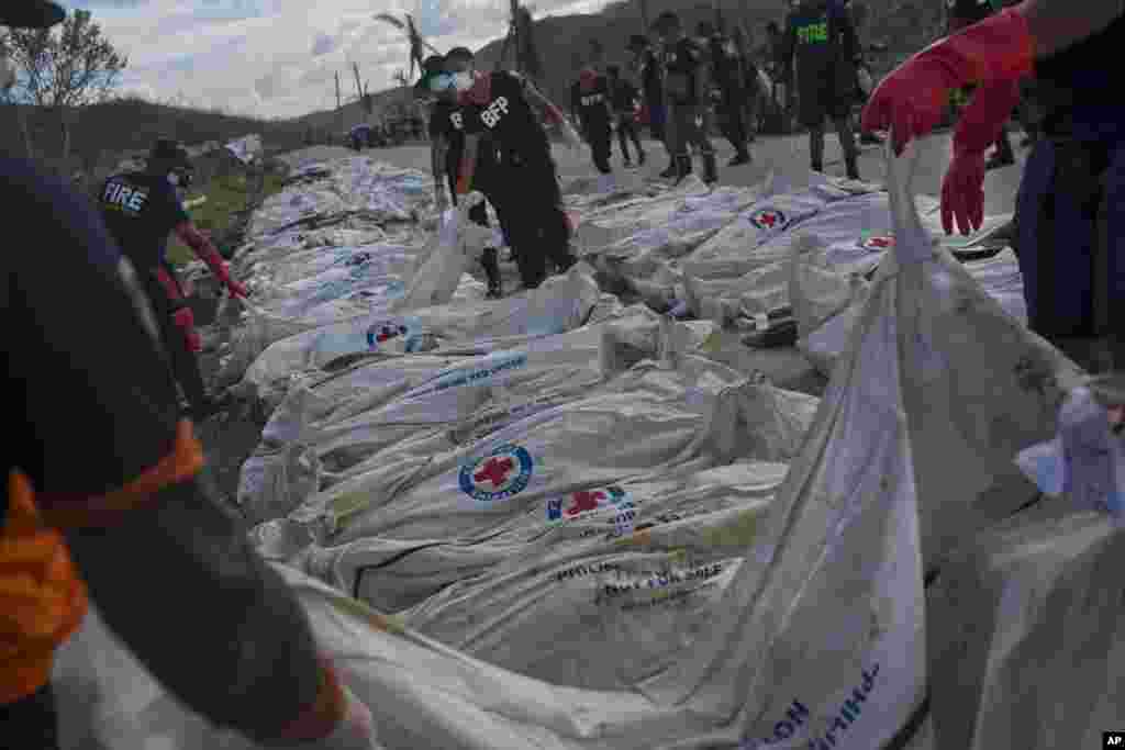 Firemen unload Typhoon Haiyan victims in body bags from a truck on the roadside until forensic experts can register and bury them in a mass grave outside of Tacloban, Philippines, Nov. 19, 2013. 