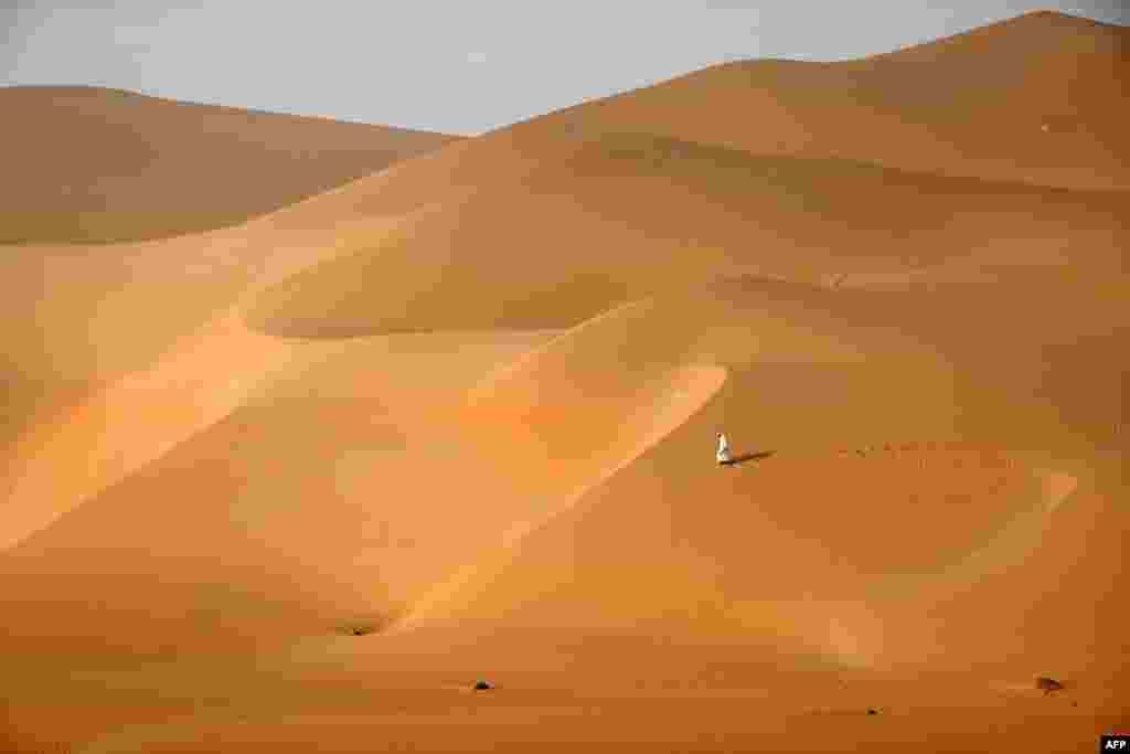 An Emirati man walks across the dunes in the Rimah desert, west of Al-Ain in the United Arab Emirates.