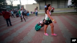 A Cuban migrant walks to a government organized bus that will take her and other Cuban migrants to the airport in La Cruz, Costa Rica, Tuesday, Jan. 12, 2016.