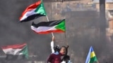 FILE - Sudanese demonstrators raise national flags as they take part in a protest in the city of Khartoum Bahri, the northern twin city of the capital, to demand the government's transition to civilian rule, Oct. 21, 2021.