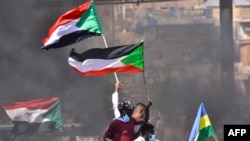 Para demonstran mengibarkan bendera Sudan dalam unjuk rasa yang berlangsung di wilayah Khartoum Bahri, yang terletah di sebalah utara ibu kota Sudan, Khartoum, pada 21 Oktober 2021. Unjuk rasa tersebut menuntut transisi sepenuhnya kepada pemerintahan sipil. (Foto: AFP)