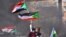FILE - Sudanese demonstrators raise national flags as they take part in a protest in the city of Khartoum Bahri, the northern twin city of the capital, to demand the government's transition to civilian rule, Oct. 21, 2021.