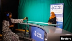 FILE - Shukri Mohamed Abdi and Fathi Mohamed Ahmed, journalists at Bilan Media, Somalia's first all-women media team, use a mobile to record the news inside the Bilan Media studios in Mogadishu, Somalia August 20, 2023. 