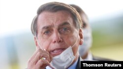 El presidente de Brasil, Jair Bolsonaro ajusta su tapabocas mientras sale del Palacio de la Alvorada en Brasilia.