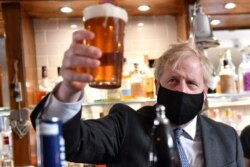 FILE - Britain's Prime Minister Boris Johnson holds up a pint during a visit to The Mount Tavern Pub and Restaurant on the local election campaign trail in Wolverhampton, West Midlands, Britain, Apr. 19, 2021. (Jacob King/PA Wire/Pool via Reuters)