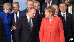 FILE - German Chancellor Angela Merkel, right, chats with Russian President Vladimir Putin after the family photo on the first day of the G-20 summit in Hamburg, northern Germany, July 7, 2017.