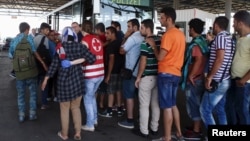 Migrants picked up within Austria near the border with Hungary line up at a makeshift camp in Nickelsdorf to be transported to other processing facilities, Aug. 29, 2015.