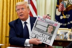 FILE - President Donald Trump holds up a copy of the New York Post as he speaks before signing an executive order aimed at curbing protections for social media giants, in the Oval Office of the White House, May 28, 2020.
