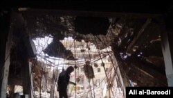 FILE -- Tahany Saleh walks through a pile of debris at the gate of Mosul University’s Central Library as she works with her volunteer team to rescue books in the burned building, Mosul, Iraq, May 2017. 