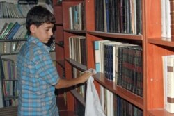 Amjad, 14, cleans shelves at the secret library in Daraya, a town in southwest Damascus, Syria. (Photo courtesy of Daraya Council Media Team)