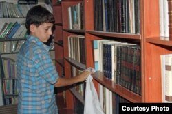 Amjad, 14, cleans shelves at the secret library in Daraya, a town in southwest Damascus, Syria. (Photo courtesy of Daraya Council Media Team)