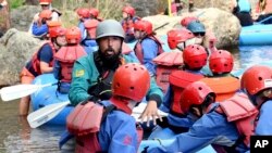 Kyle Lester, a rafting guide for Rocky Mountain Adventures, teaches a group basic safety measures and rowing techniques before floating down the Cache la Poudre River near Fort Collins, Colo., Wednesday, June 23, 2021. (AP Photo/Thomas Peipert)